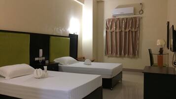A hotel room with two beds, a desk, a telephone, an air conditioner, and a curtain.