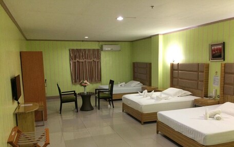 A hotel room with two single beds, a small dining table with chairs, a TV, and a desk with a chair.