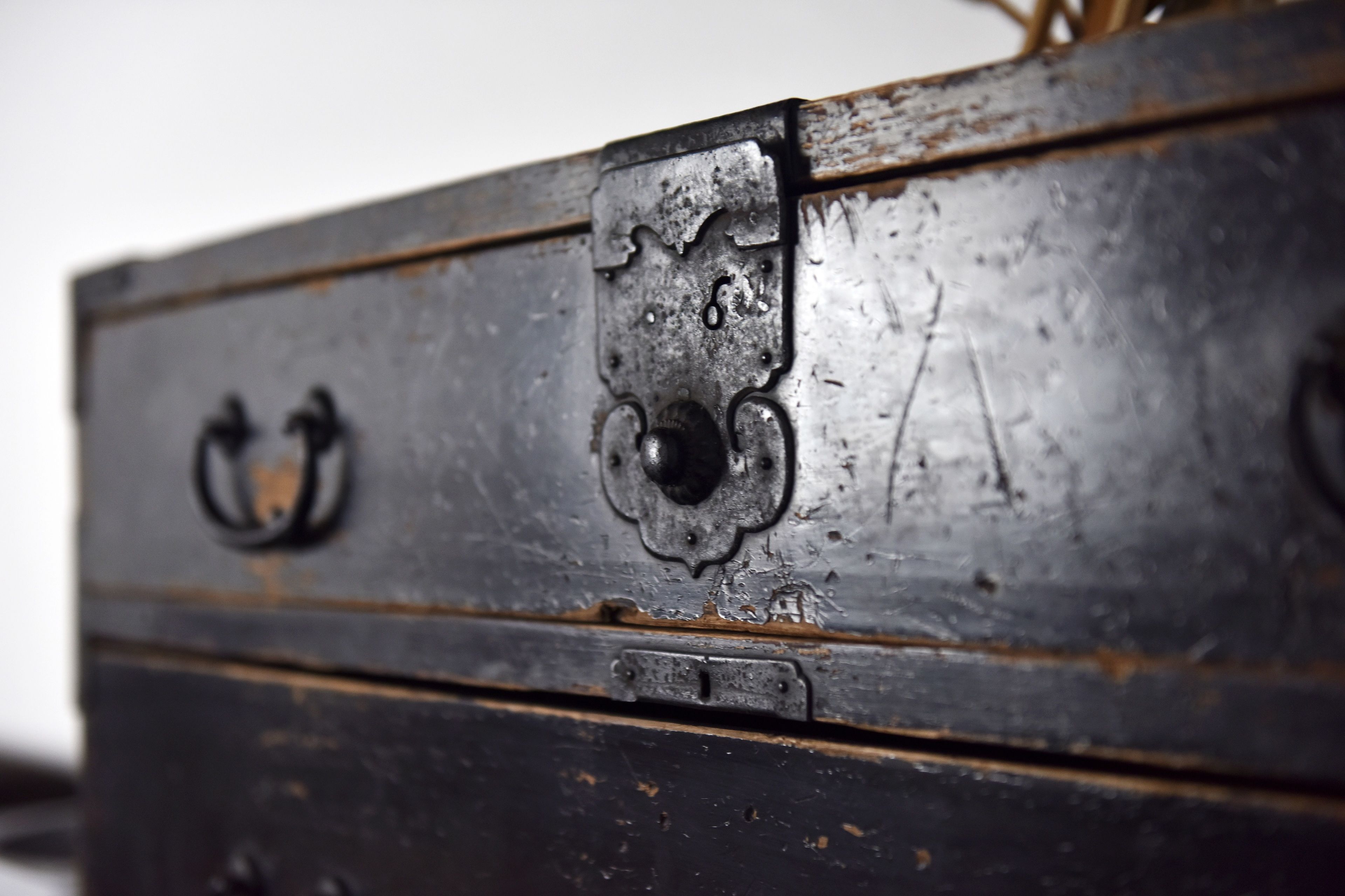 A close-up of a dark wooden chest with metal handles and a latch.