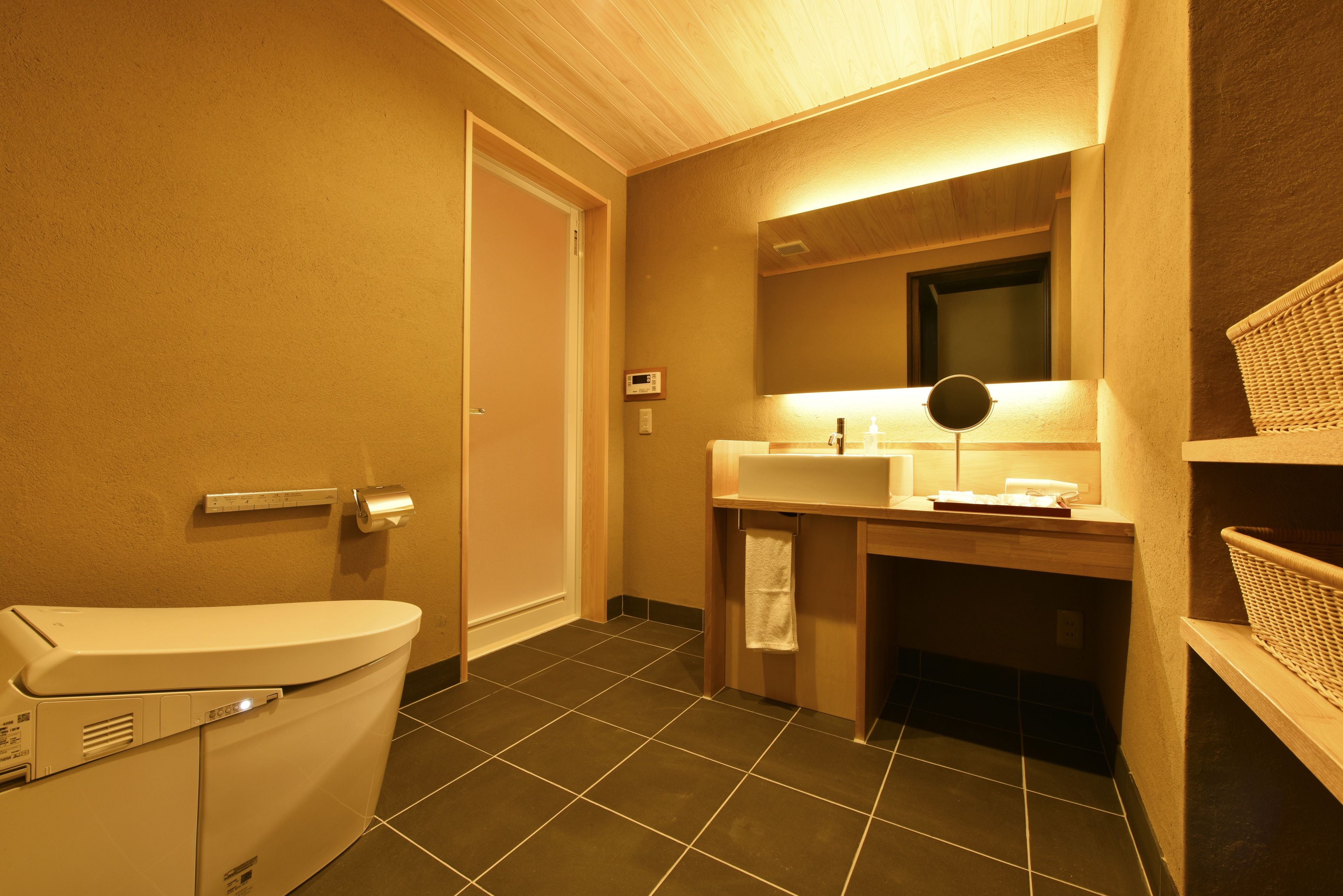 A bathroom with a toilet, sink, mirror, and a wall-mounted heater.