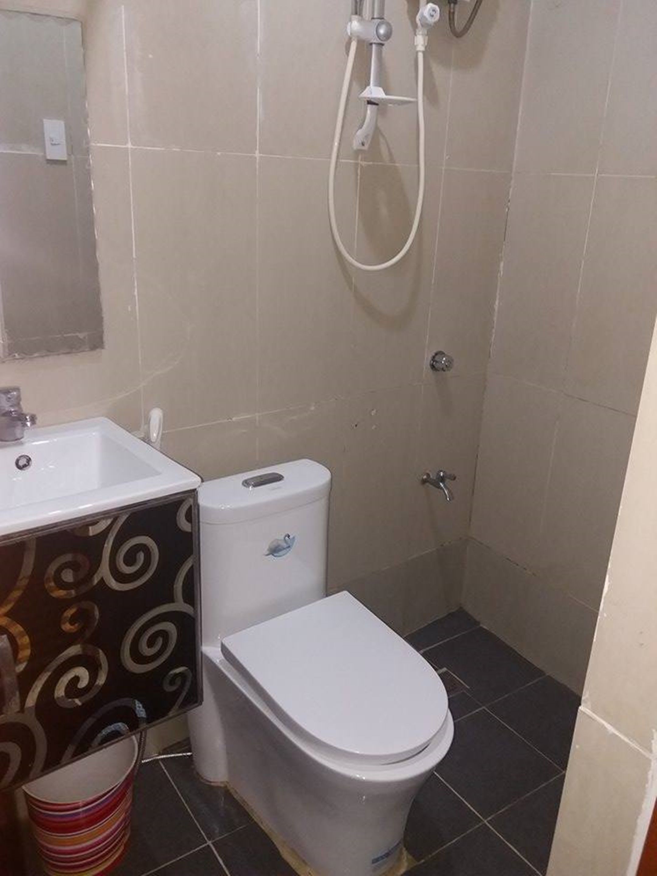 Et lille badeværelse med toilet, håndvask og bruser.