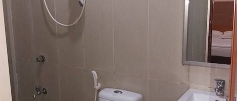 A bathroom with a toilet, a shower, and a sink.