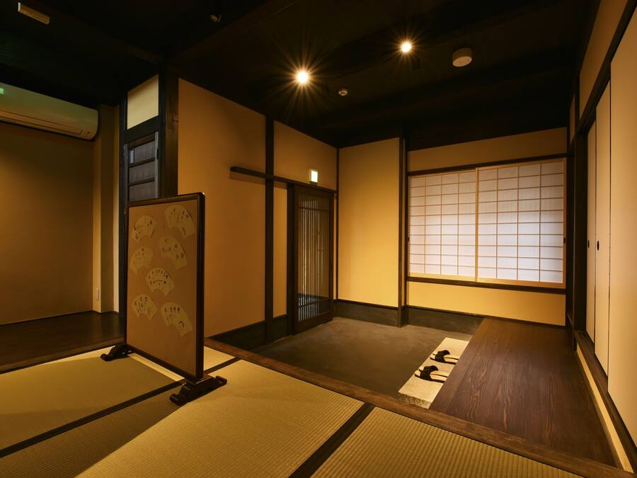 Una habitación japonesa tradicional con suelo de tatami, paneles shoji y una puerta corredera.