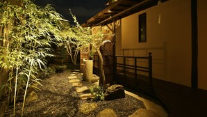 A garden pathway with stepping stones, bamboo plants, and a wooden fence. - KURAYA Senbonsanjo (Kyoto)