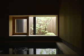 Quarto com janela que dá para uma cerca de madeira e vegetação.