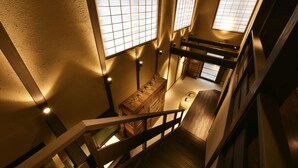 A staircase with wooden railings and a wooden bench. There are multiple windows with grid patterns. - KURAYA Nanseicho (Kyoto)
