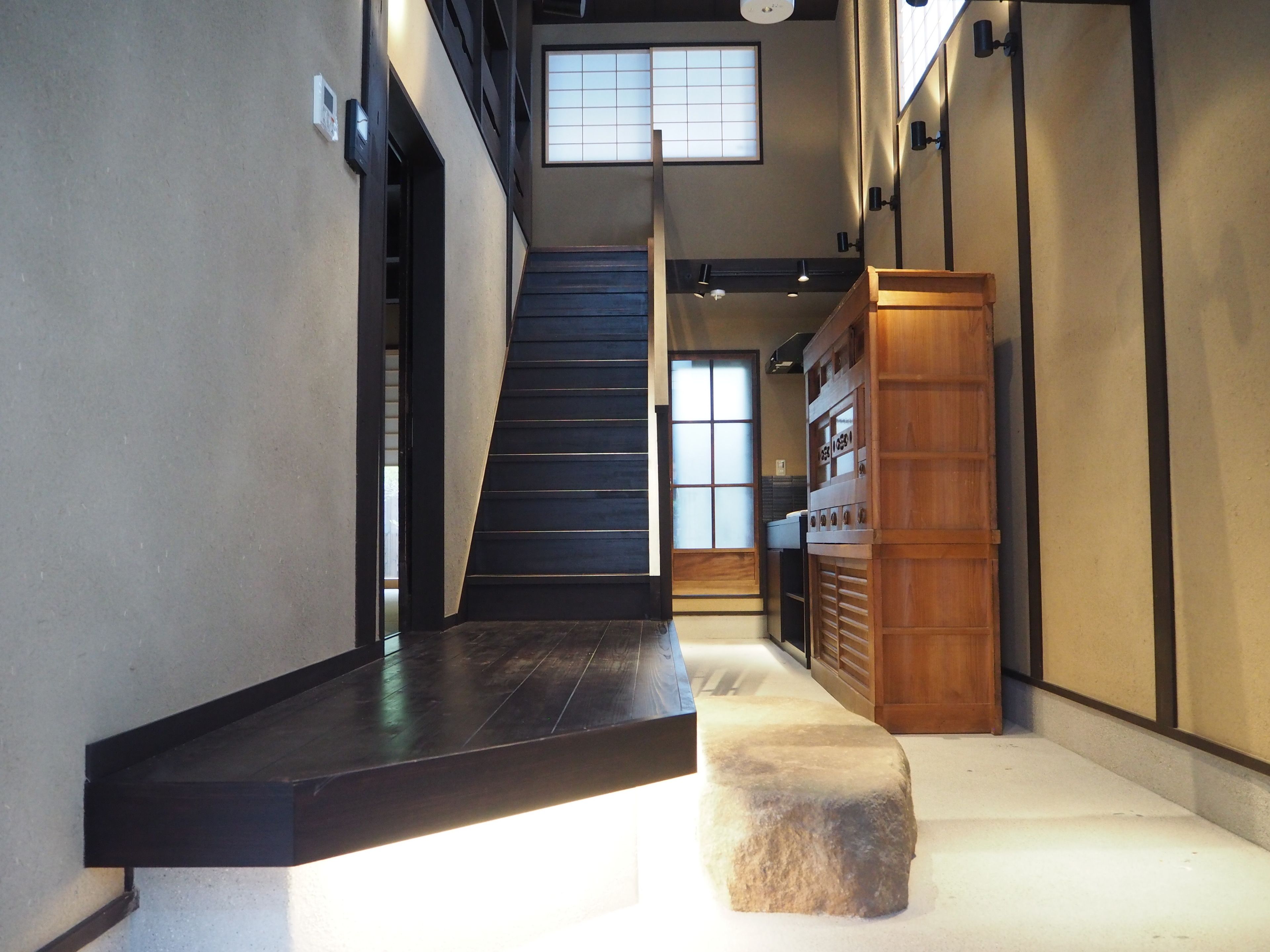 A modern interior with a staircase, a wooden bench, and a stone slab.