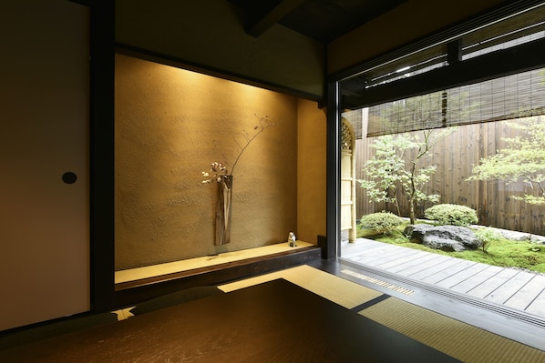 A traditional Japanese interior with tatami flooring, a low wooden table, and a minimalist decor including a branch sculpture.