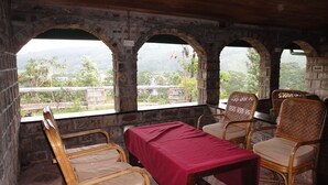 A room with a table and four chairs, a red tablecloth, and three arched windows overlooking a landscape. - Castlereigh Holiday Bungalow (Hatton)