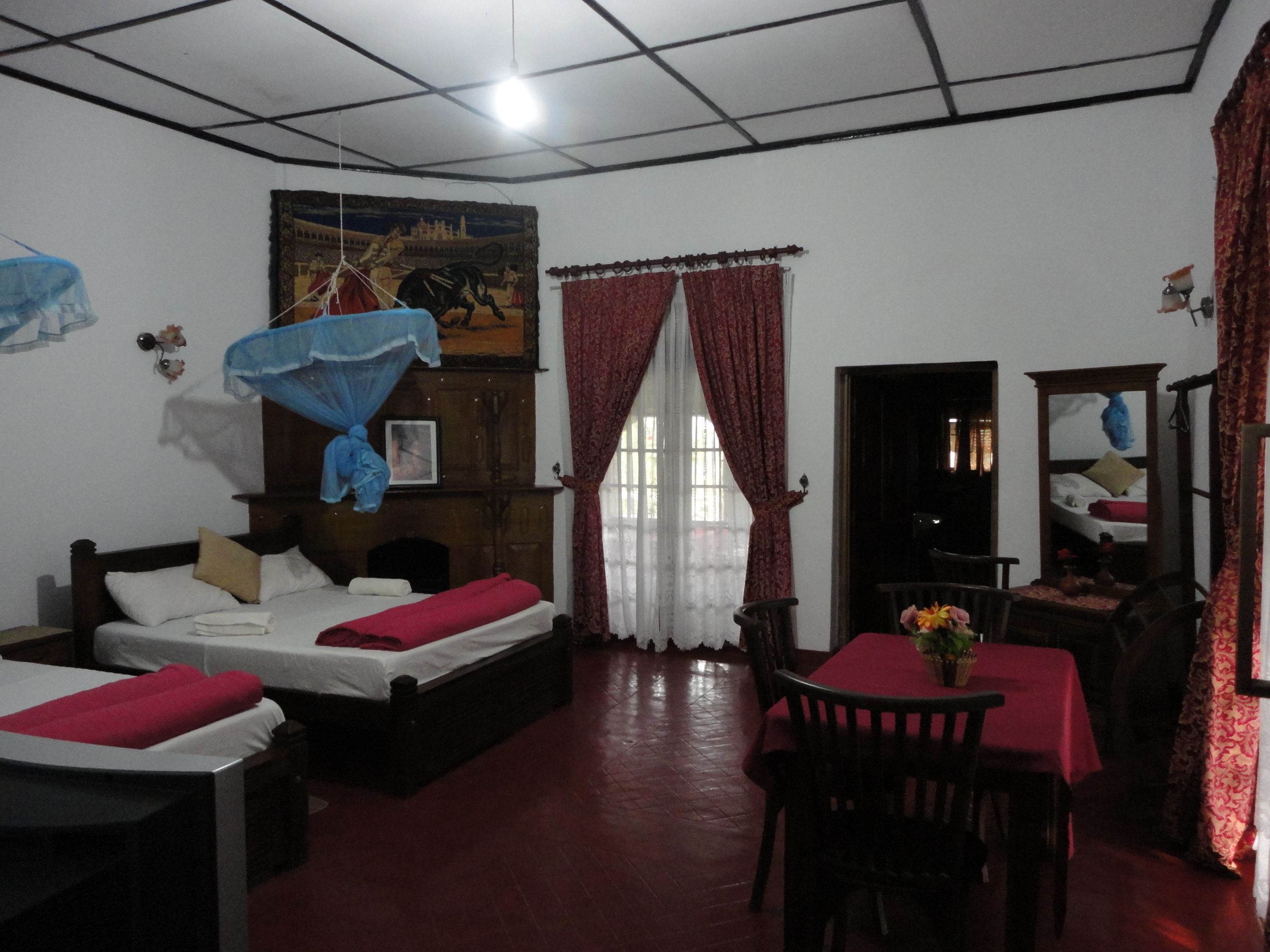 A room with two beds, a dining table, and a large painting on the wall.