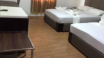 A hotel room with two single beds, a desk, a chair, and a television.