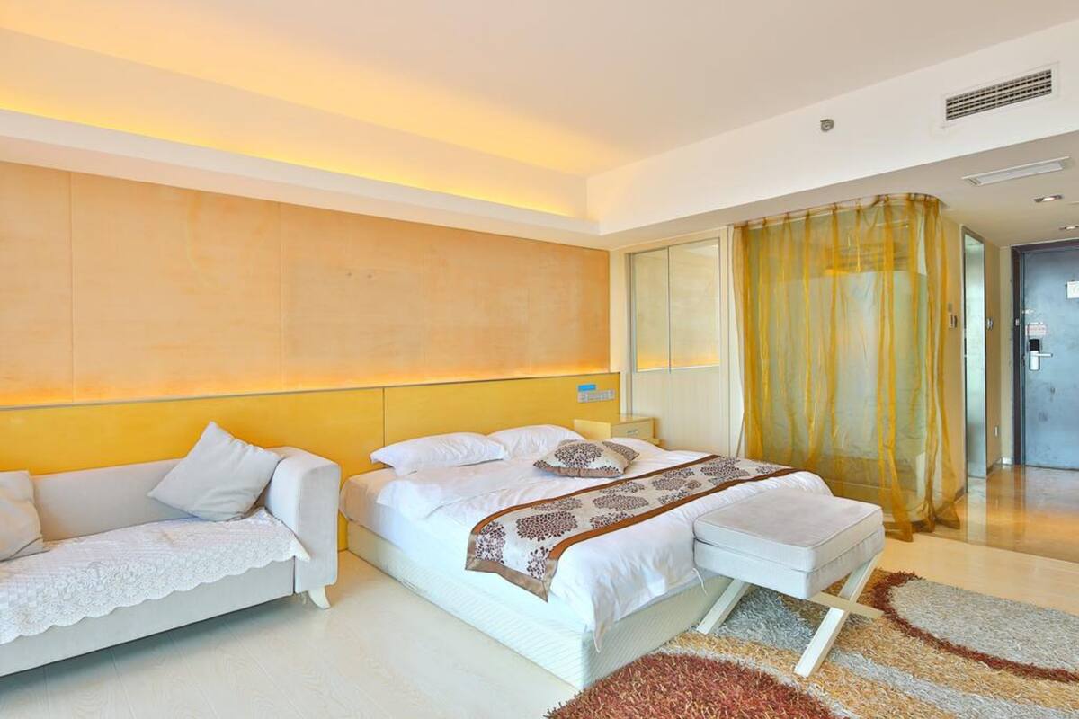 Una habitación de hotel moderna con cama, sofá y un espejo grande.