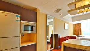 Habitación de hotel con microondas, refrigerador, cama con almohadas rojas y un gran ventanal con cortinas.