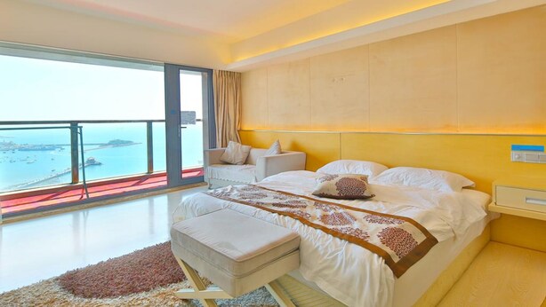 Un dormitorio moderno con una cama grande, vista al mar y un balcón.