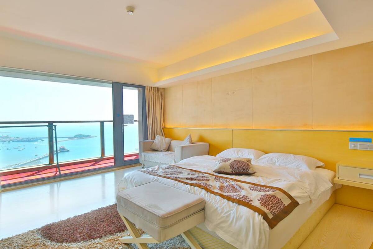 Un dormitorio moderno con una cama grande, vista al mar y un balcón.