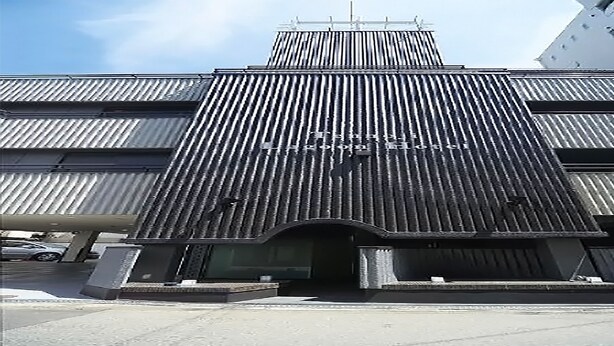 A modern building with a corrugated metal facade and a prominent entrance. - Tennoji Lagoon Hotel (Osaka)