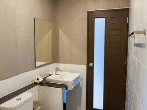 A bathroom with a toilet, sink, and mirror. - BR Grand Hotel (Hat Yai)