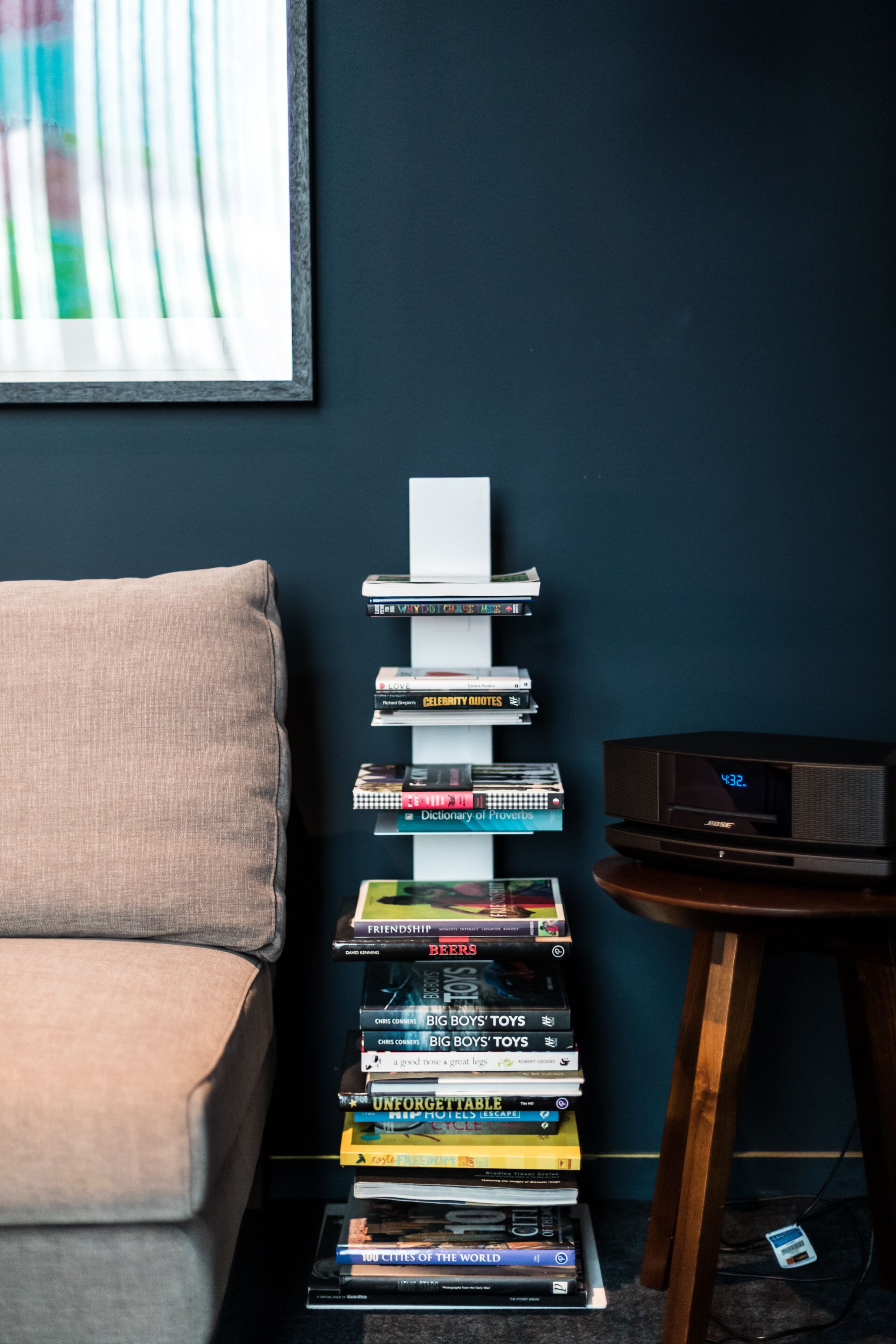 Ein Bücherstapel auf einem Tisch neben einer Couch und einer Uhr.