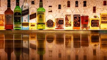 A variety of liquor bottles displayed on a reflective surface with a speckled background.