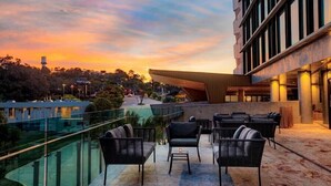 Una terraza en la azotea con mobiliario exterior y vistas al atardecer.