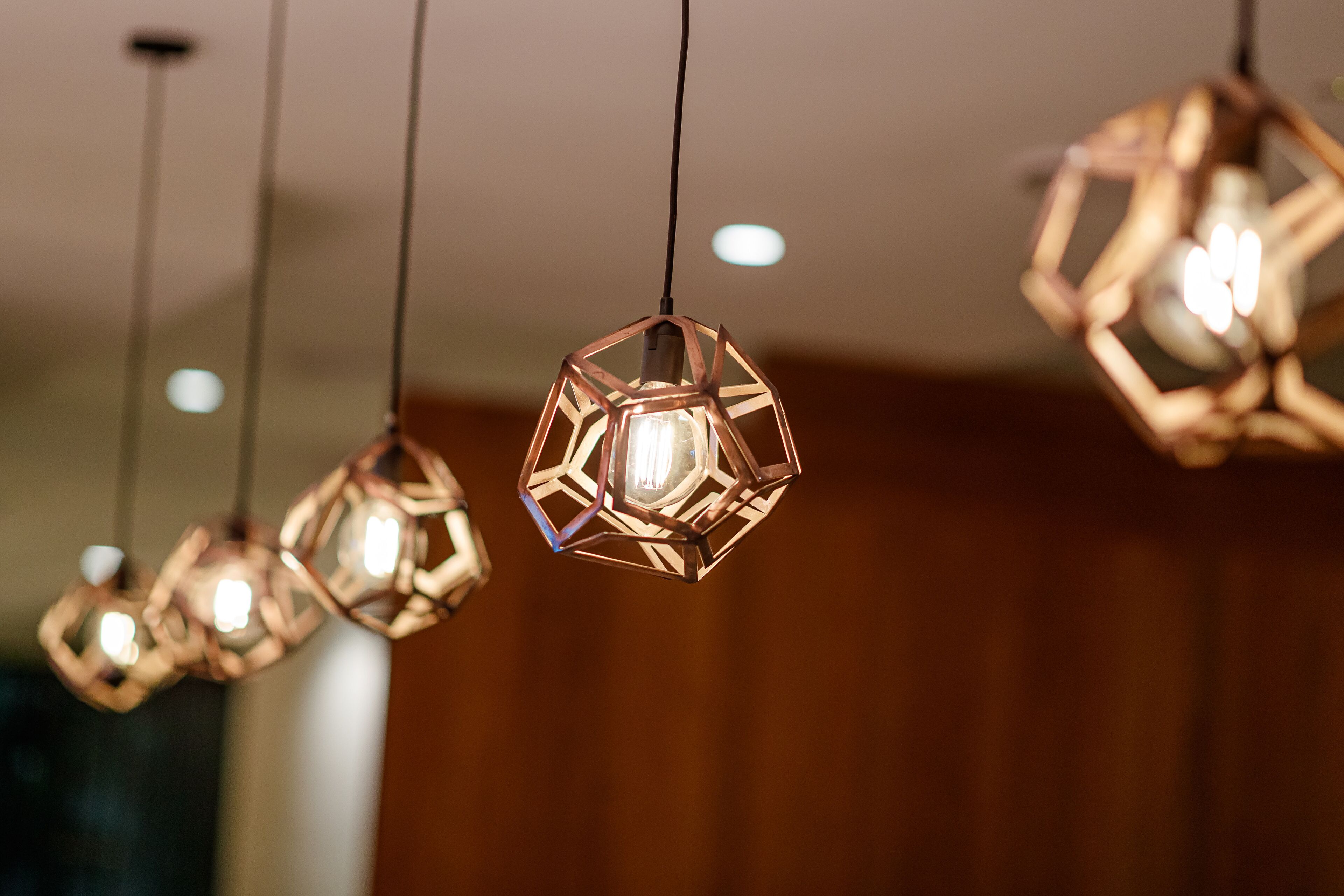 A series of hexagonal pendant lights with exposed bulbs, hanging from a ceiling.