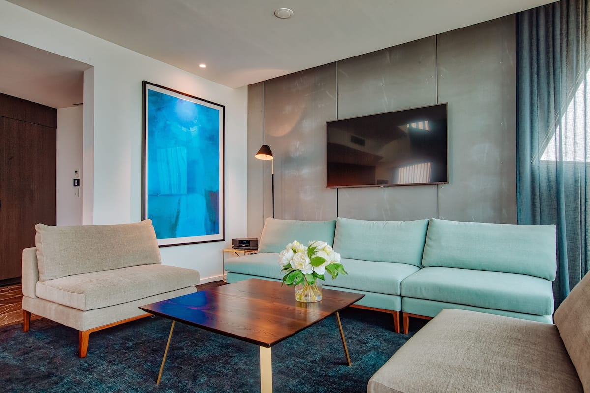 A modern living room with a sofa, a coffee table, and a TV mounted on the wall.