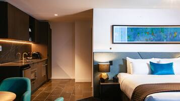 A hotel room with a bed, bedside table, lamp, and a painting on the wall.