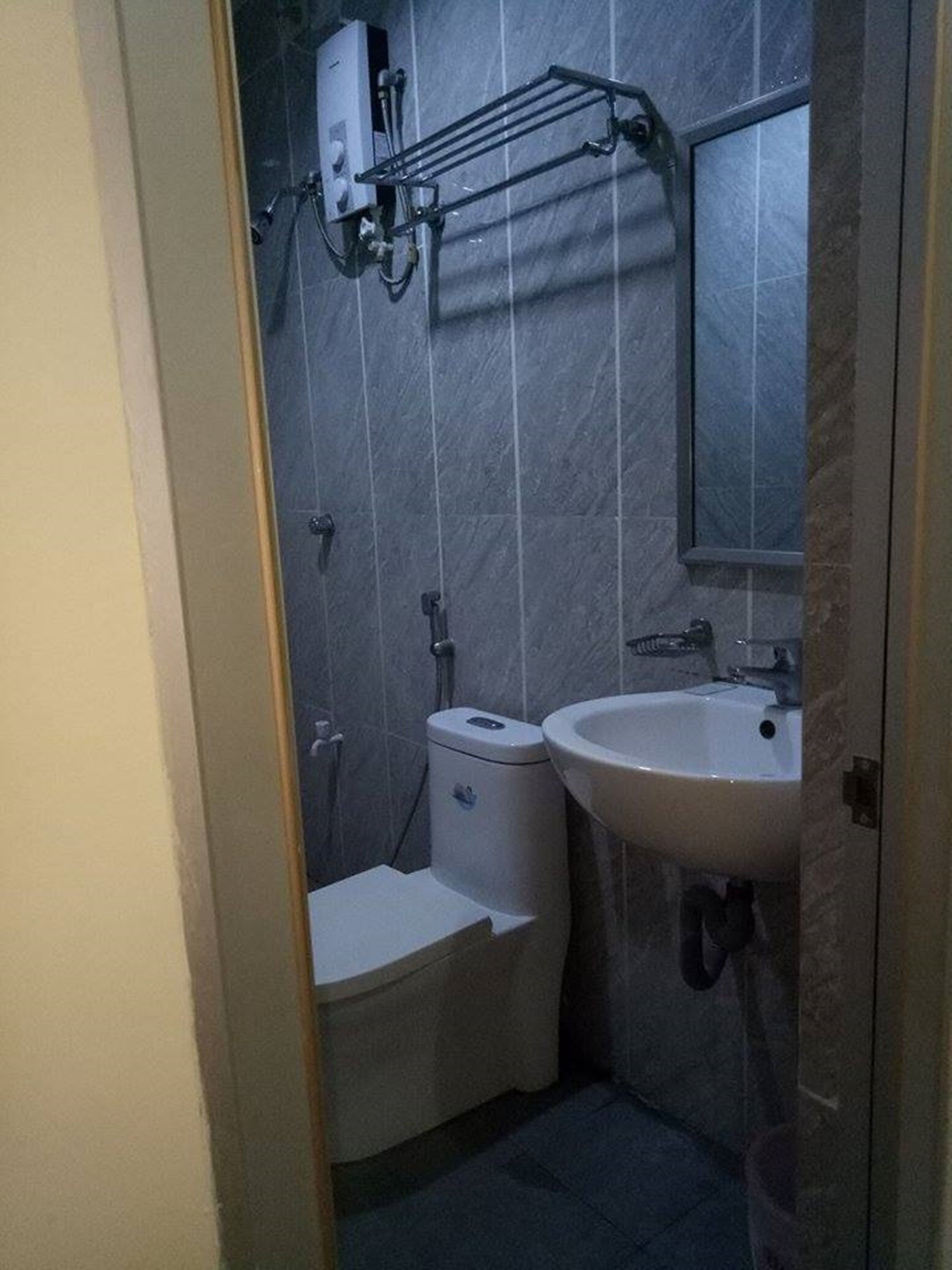 A small bathroom with a toilet, sink, and a mirror.