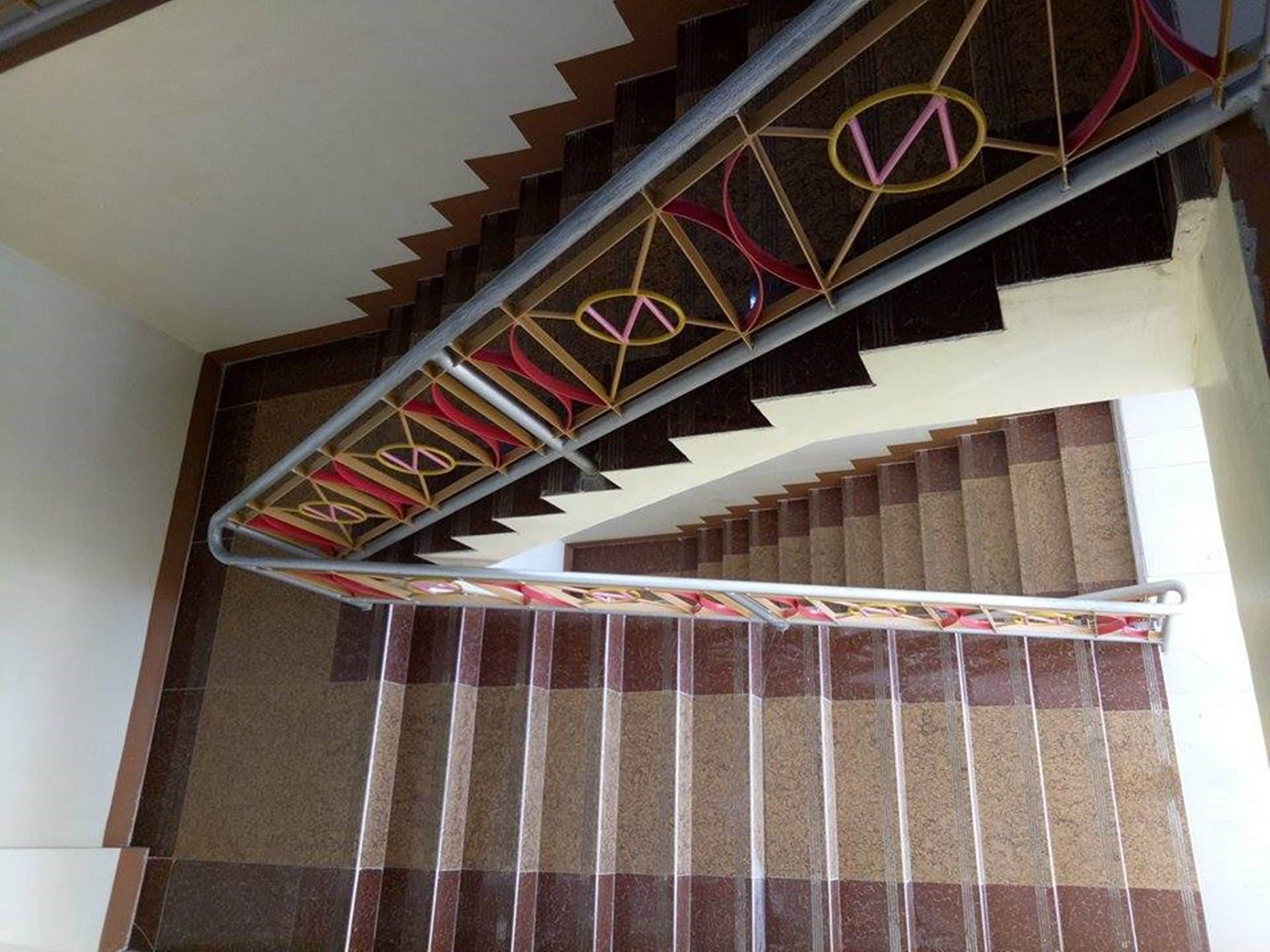 A staircase with a geometric patterned handrail and a checkered floor.