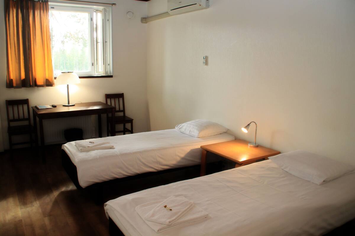 A room with two beds, a desk, and a chair.