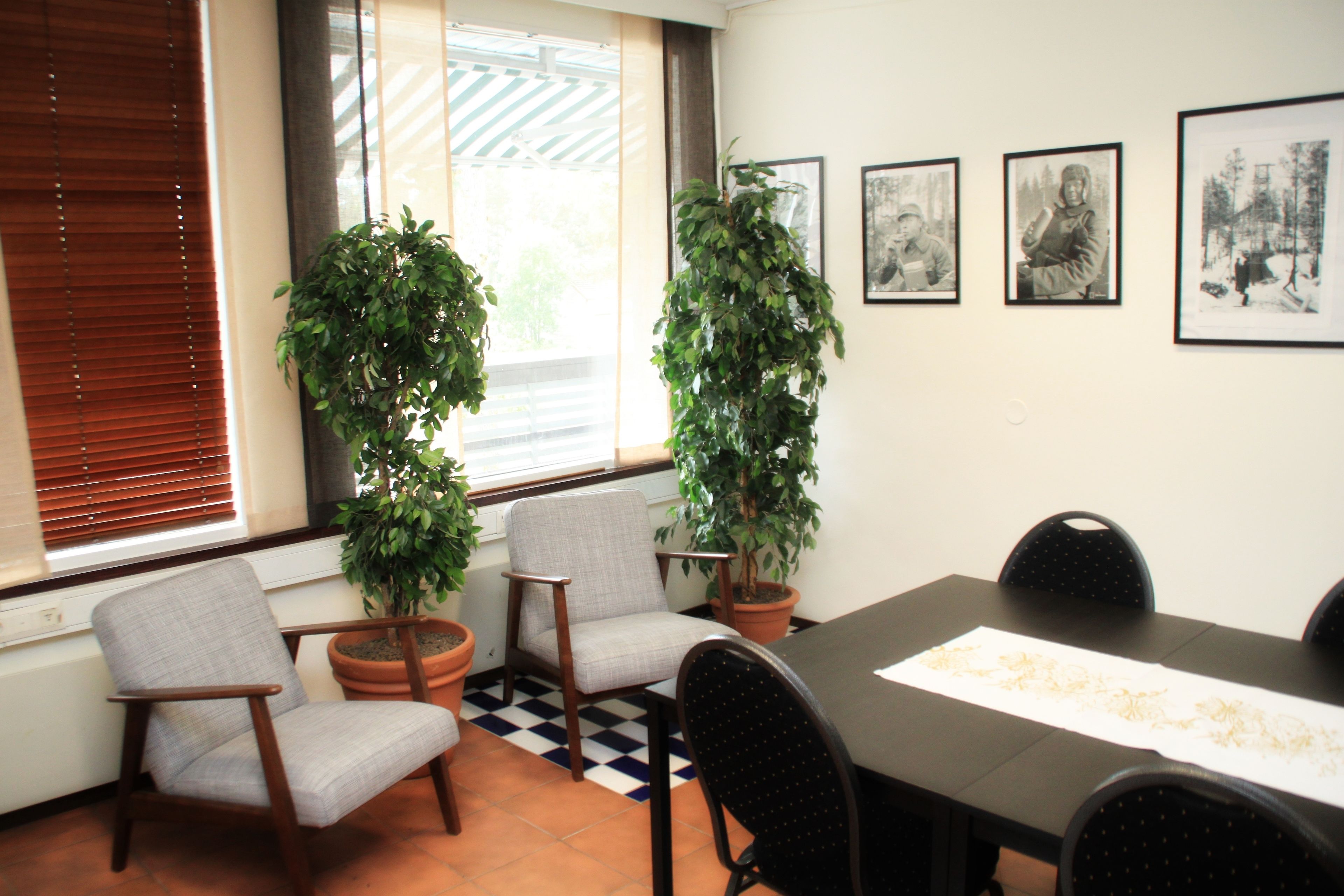 Une salle de conférence avec une longue table, deux plantes en pot et trois photographies encadrées accrochées au mur.