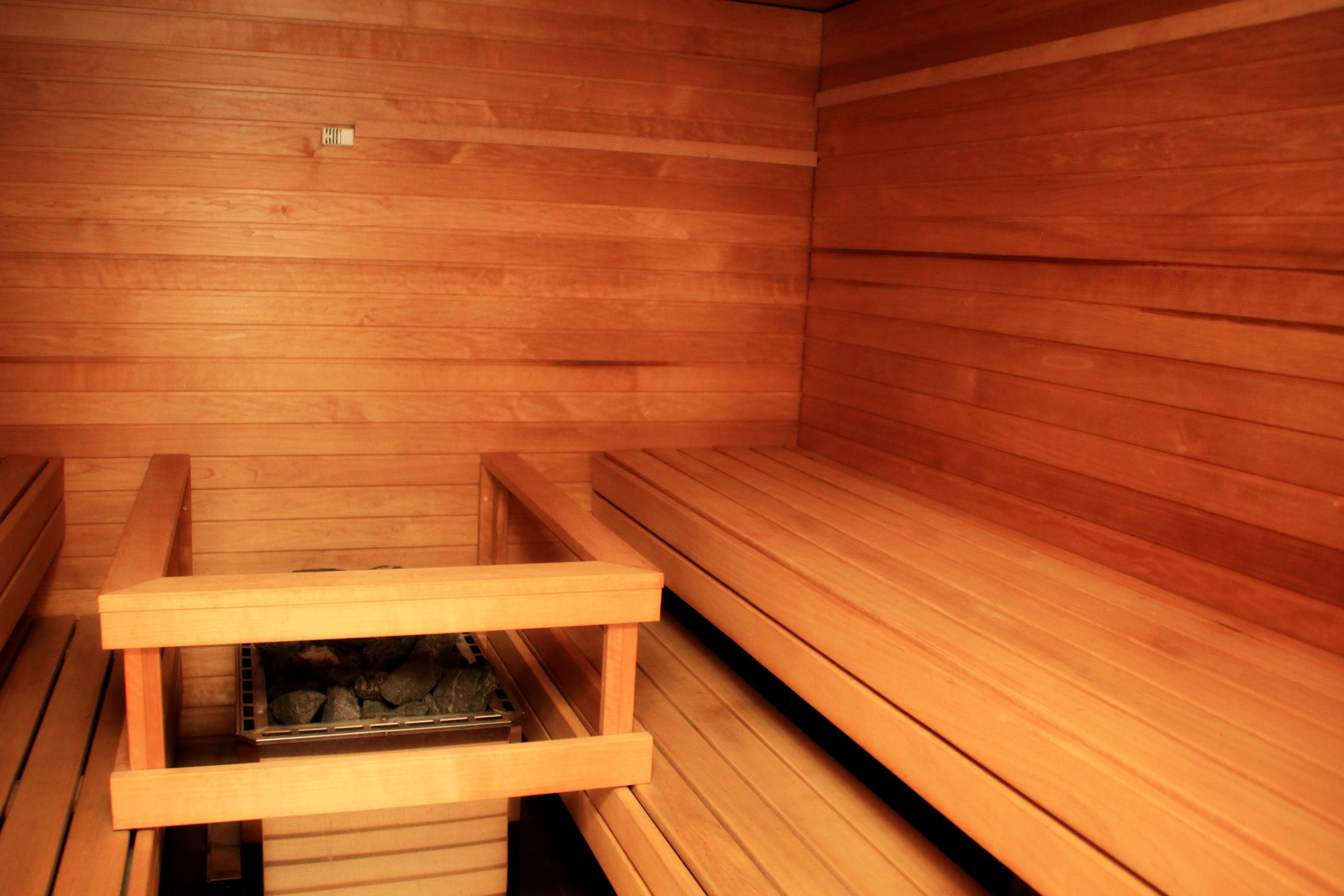 A sauna room with wooden benches and a bench with a heating element.