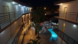 Ein Hotelinnenhof mit Schwimmbad, mehreren Balkonen und einer überdachten Sitzgelegenheit.