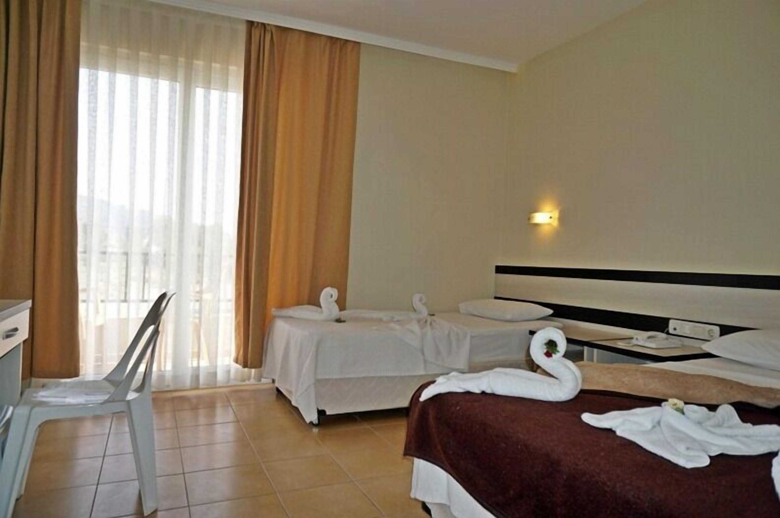 A hotel room with two beds, a desk, and a chair.