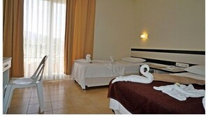 Ein Hotelzimmer mit zwei Betten, einem Schreibtisch, einem Stuhl und einem Fenster mit Vorhängen.