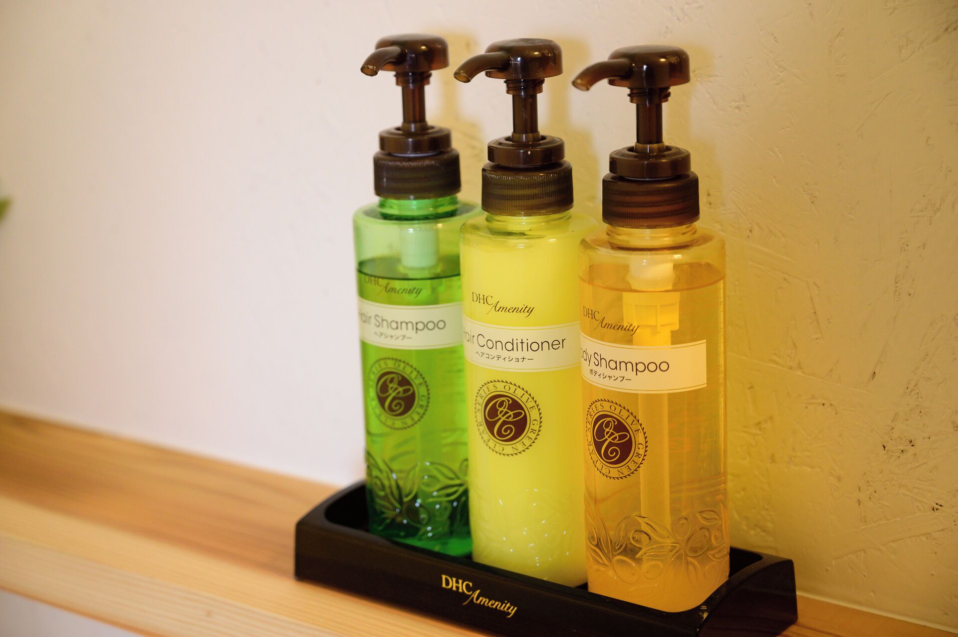 Three bottles of hair care products in a black tray with a logo.