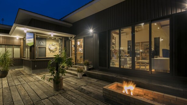 Een modern gebouw met een vuurkorf, plantenbakken en een bord dat de hoofdingang aangeeft.