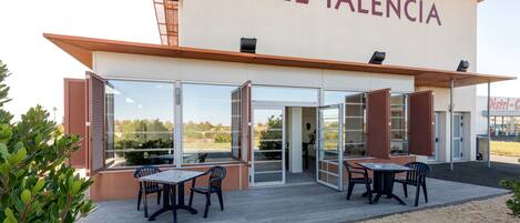 A hotel named "HOTEL TALENCIA" with an outdoor seating area and a view of the surrounding landscape.