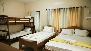 Una habitación con literas, un escritorio de madera y una cama con una manta amarilla.