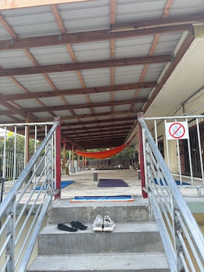 A covered outdoor area with a metal staircase leading up to a platform. - Yogi-Homestay (Koror)