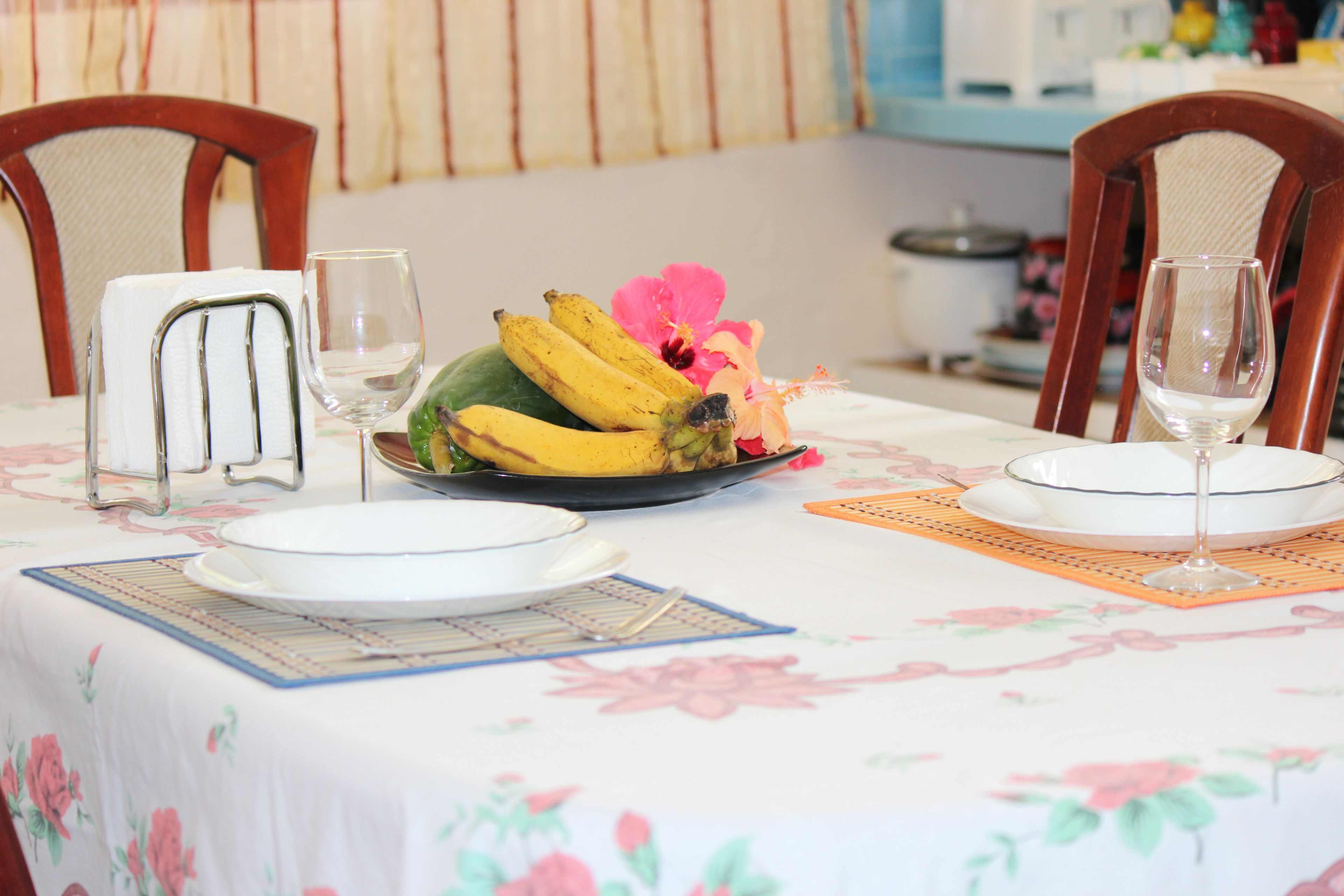 Taula de menjador preparada amb plats, un plat de fruita i vasos de vi.
