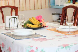 Una mesa de comedor dispuesta con platos, un frutero y copas de vino.