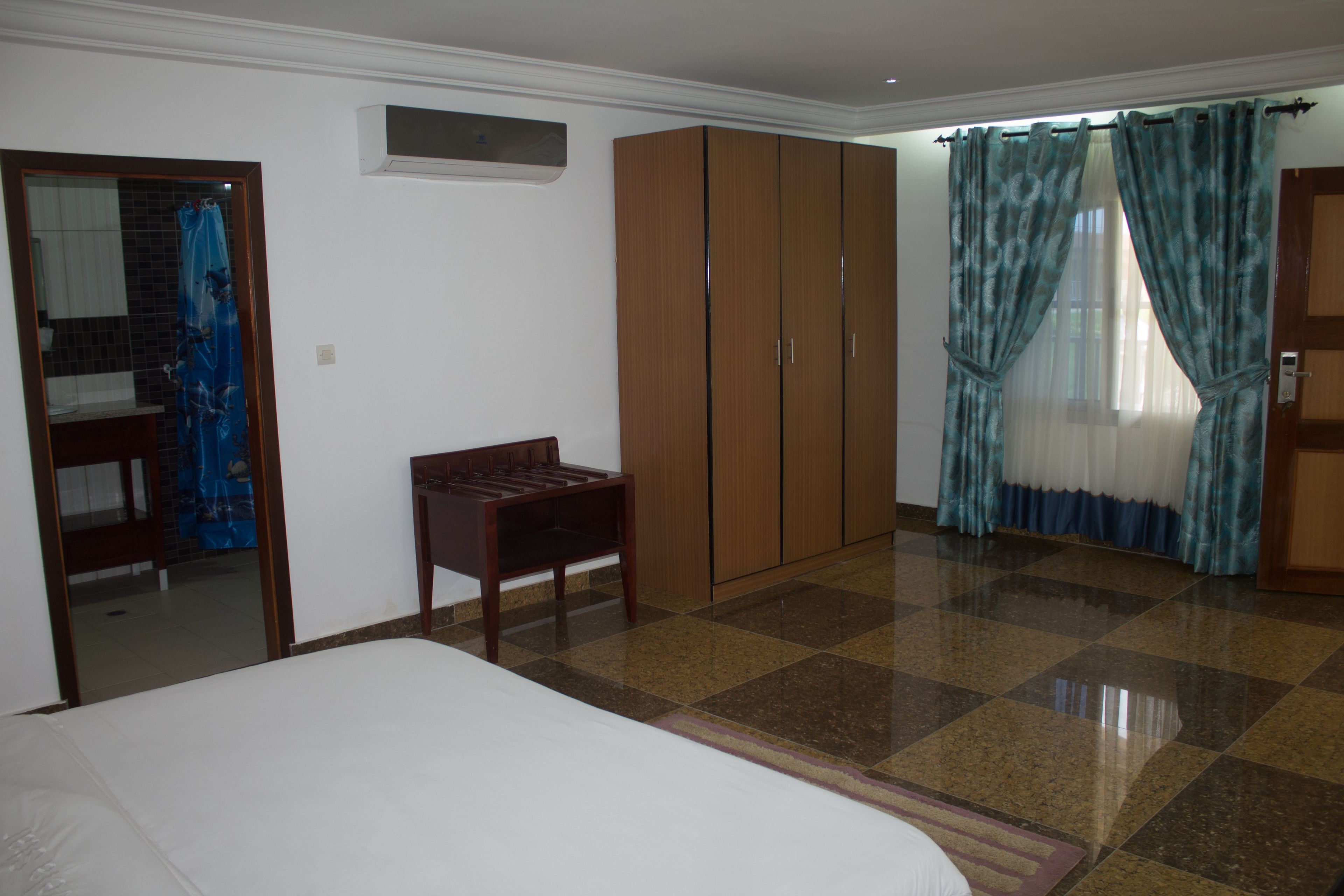 A bedroom with a bed, wooden wardrobe, and a small table.