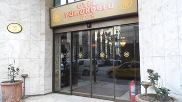 La entrada del hotel OTEI YUMUKOGLU, con fachada de mármol y puertas de cristal.