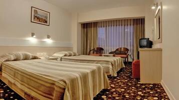 Quarto de hotel com duas camas, televisão, escrivaninha e cadeira.