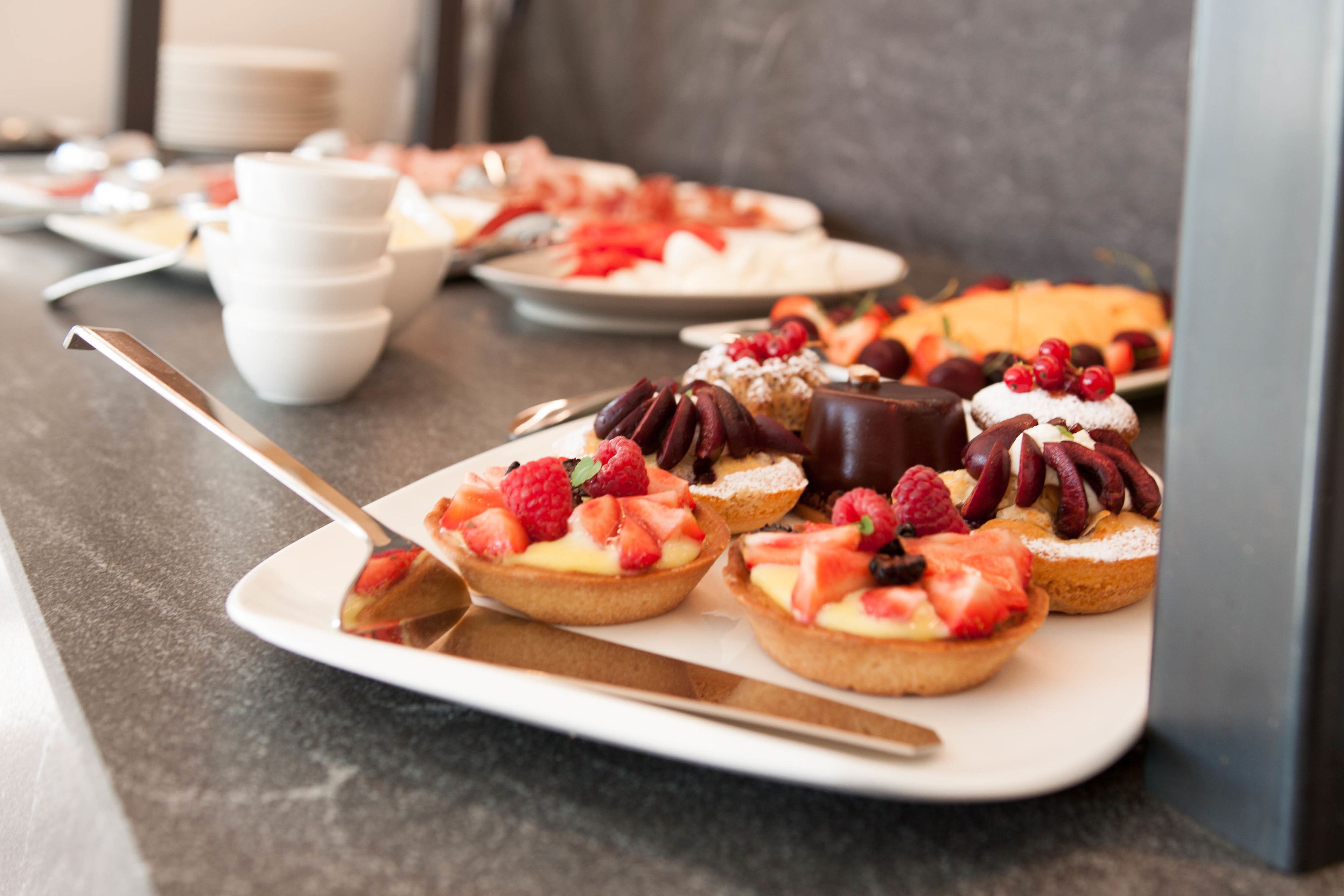Un plateau de desserts avec divers pâtisseries garnies de fruits, présentées sur une assiette blanche.
