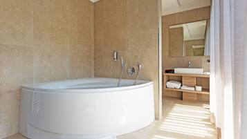 Une salle de bain moderne avec une grande baignoire sur pieds, un meuble-lavabo avec un miroir et une étagère en bois où sont posées des serviettes.