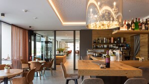 A modern restaurant with a bar area, wooden tables, and chairs.