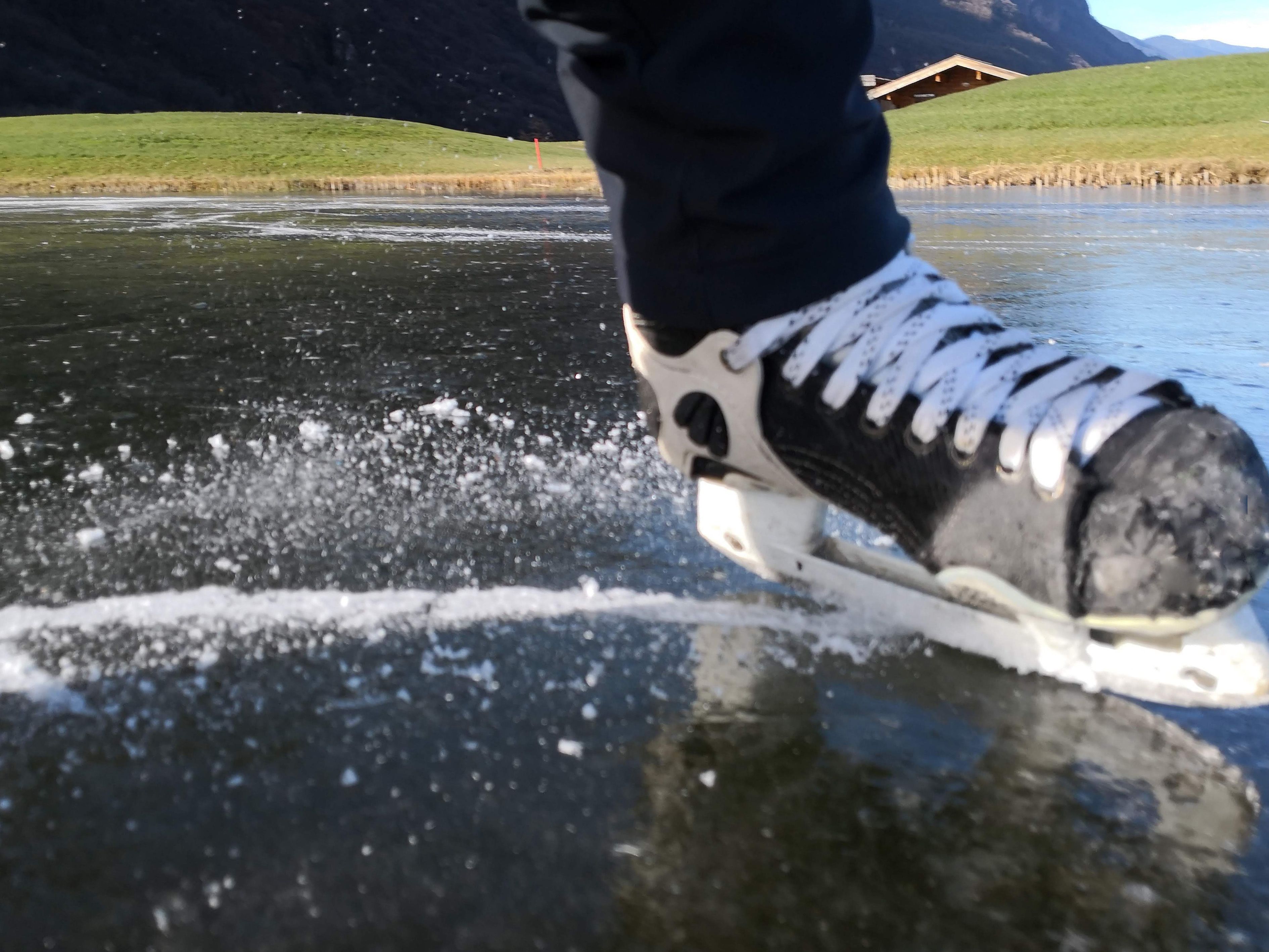 A close-up of a person ice-skating on a frozen surface with a mountainous landscape in the background.