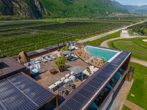 A rooftop terrace with solar panels, outdoor seating, and a swimming pool. - The Lodge Hotel (Appiano Sulla Strada del Vino)